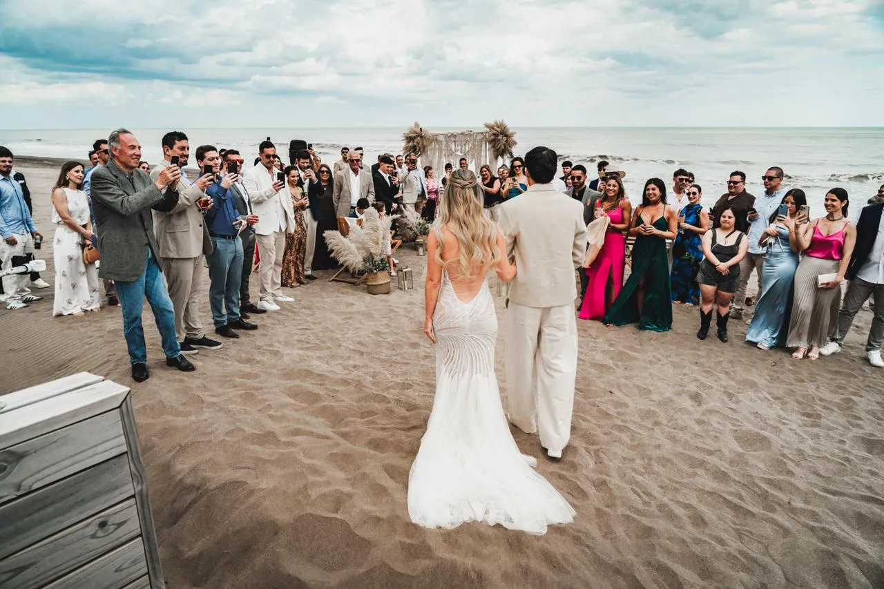 Los novios entrando por la alfombra de la ceremonia entre los invitados de pie