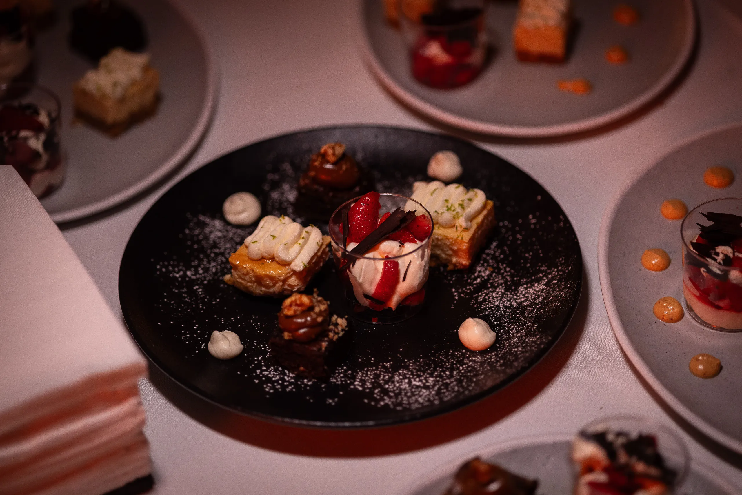 Postre emplatado sobre vajilla oscura, en la mesa tendida